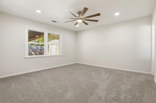 an empty room with windows and ceiling fan