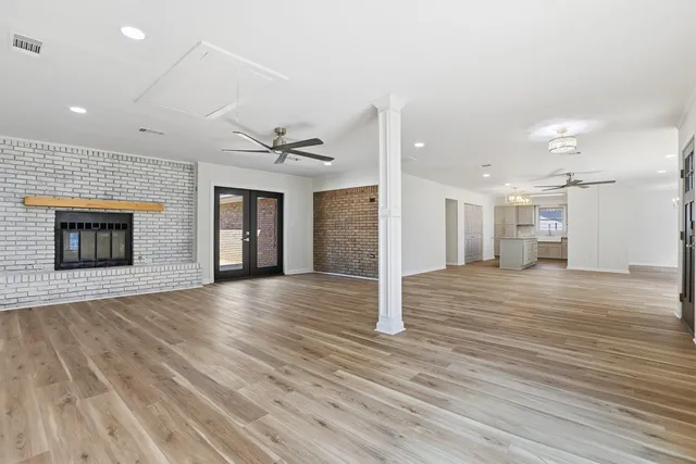 a view of an empty room with wooden floor and a kitchen