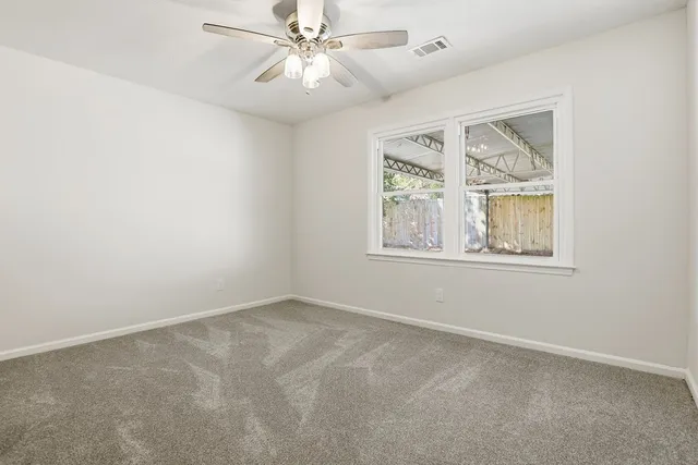 an empty room with windows and fan