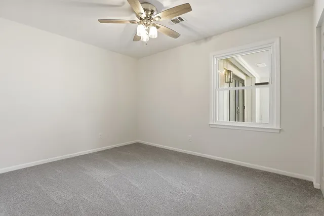 an empty room with a chandelier fan and windows