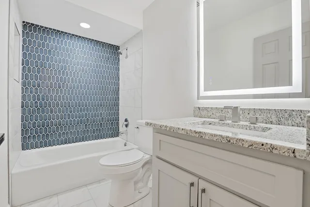 a bathroom with a granite countertop toilet a sink and a bathtub