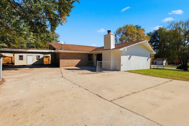 a view of a house with a yard and large tree