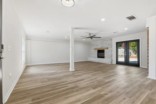 an empty room with wooden floor fireplace and windows