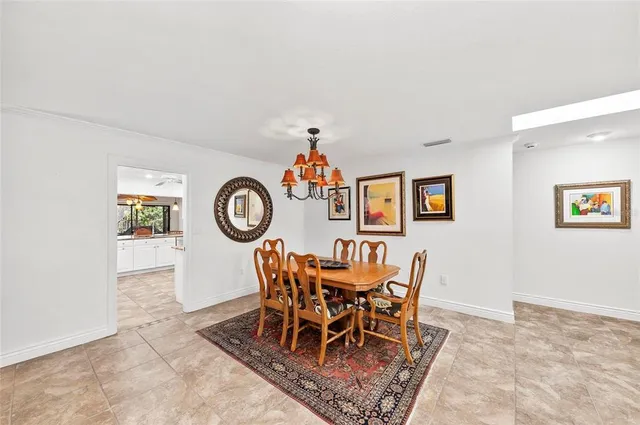 a large white kitchen with a stove a sink dishwasher a dining table and chairs with wooden floor