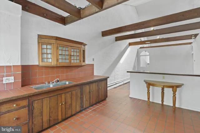 a view of a refrigerator in kitchen and an empty room