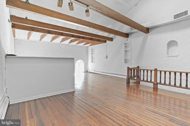 a view of an empty room with wooden floor and a large window