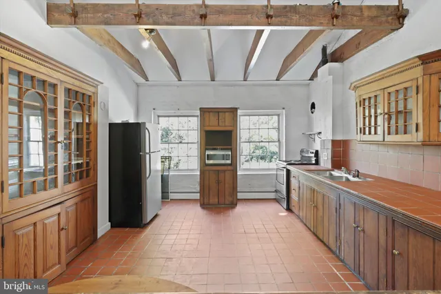 a large white kitchen with stainless steel appliances granite countertop a refrigerator and a sink