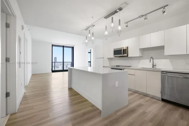 a kitchen with kitchen island granite countertop a sink cabinets and wooden floor