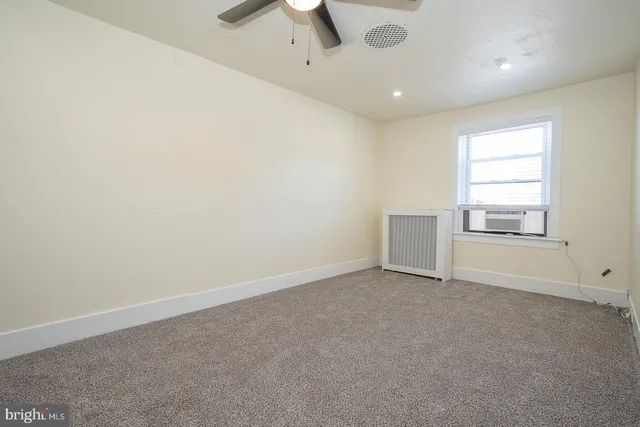 an empty room with windows and ceiling fan