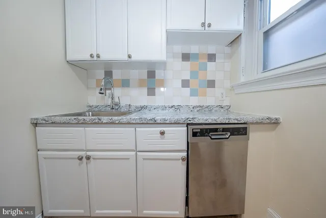 a kitchen with granite countertop white cabinets and a sink