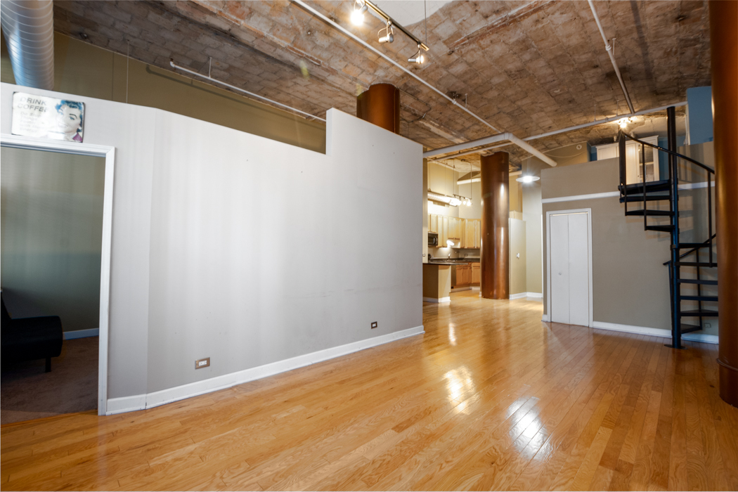 801 South Wells Street, Unit 102 Chicago, IL 60607 - Photo 16 of 26 a view of an empty room with wooden floor and a kitchen