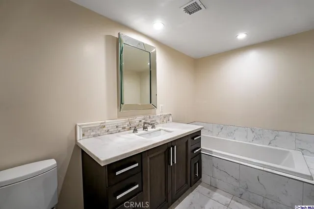 a bathroom with a sink a toilet and a large mirror