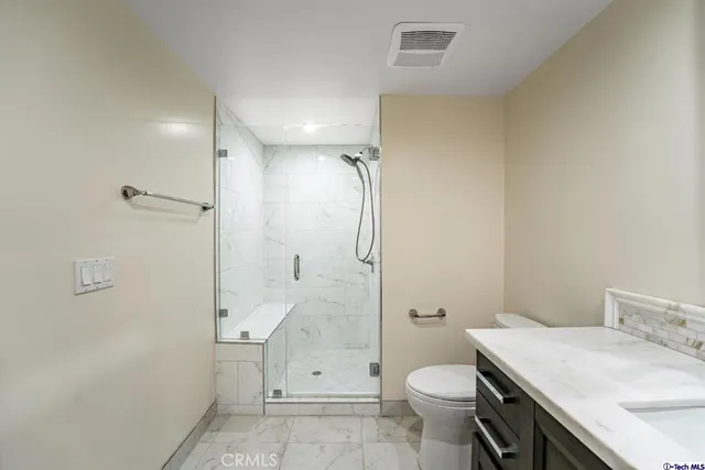 a bathroom with a granite countertop sink toilet and shower