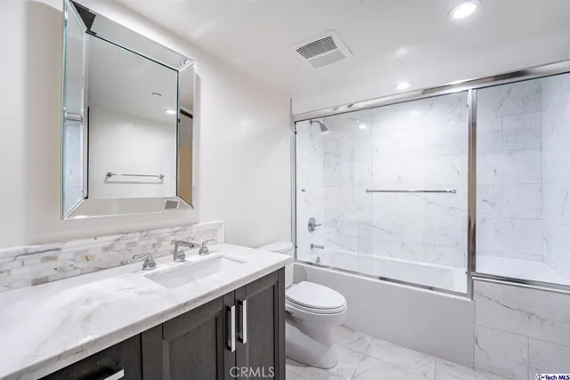 a bathroom with a granite countertop sink toilet and shower
