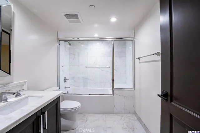 a bathroom with a granite countertop sink toilet a mirror and shower