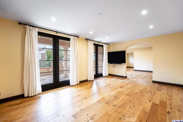 a view of an empty room with wooden floor and stairs