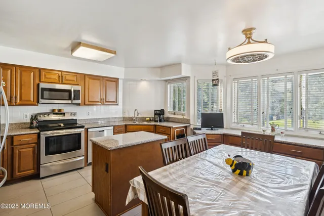 a kitchen with stainless steel appliances granite countertop a stove a sink dishwasher a dining table and chairs with wooden floor