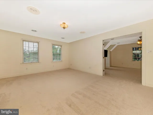 an empty room with windows and ceiling fan