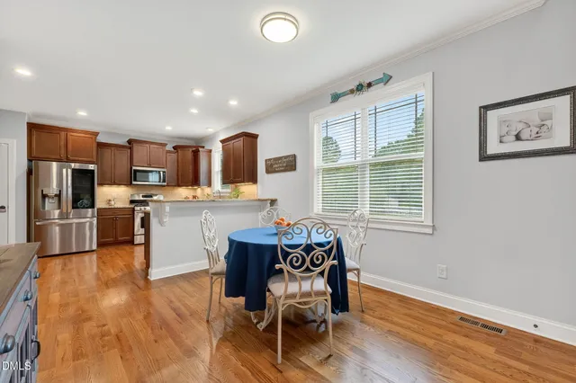 a kitchen with stainless steel appliances wooden floor and dining table
