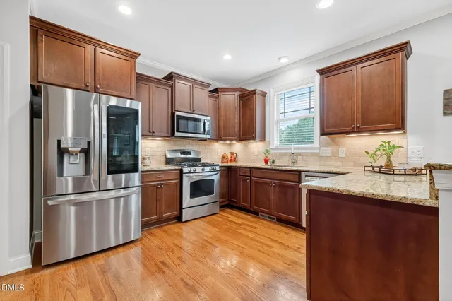 a kitchen with stainless steel appliances granite countertop a refrigerator stove microwave and sink