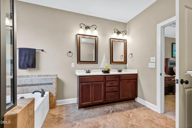 a spacious bathroom with a tub sink and mirror