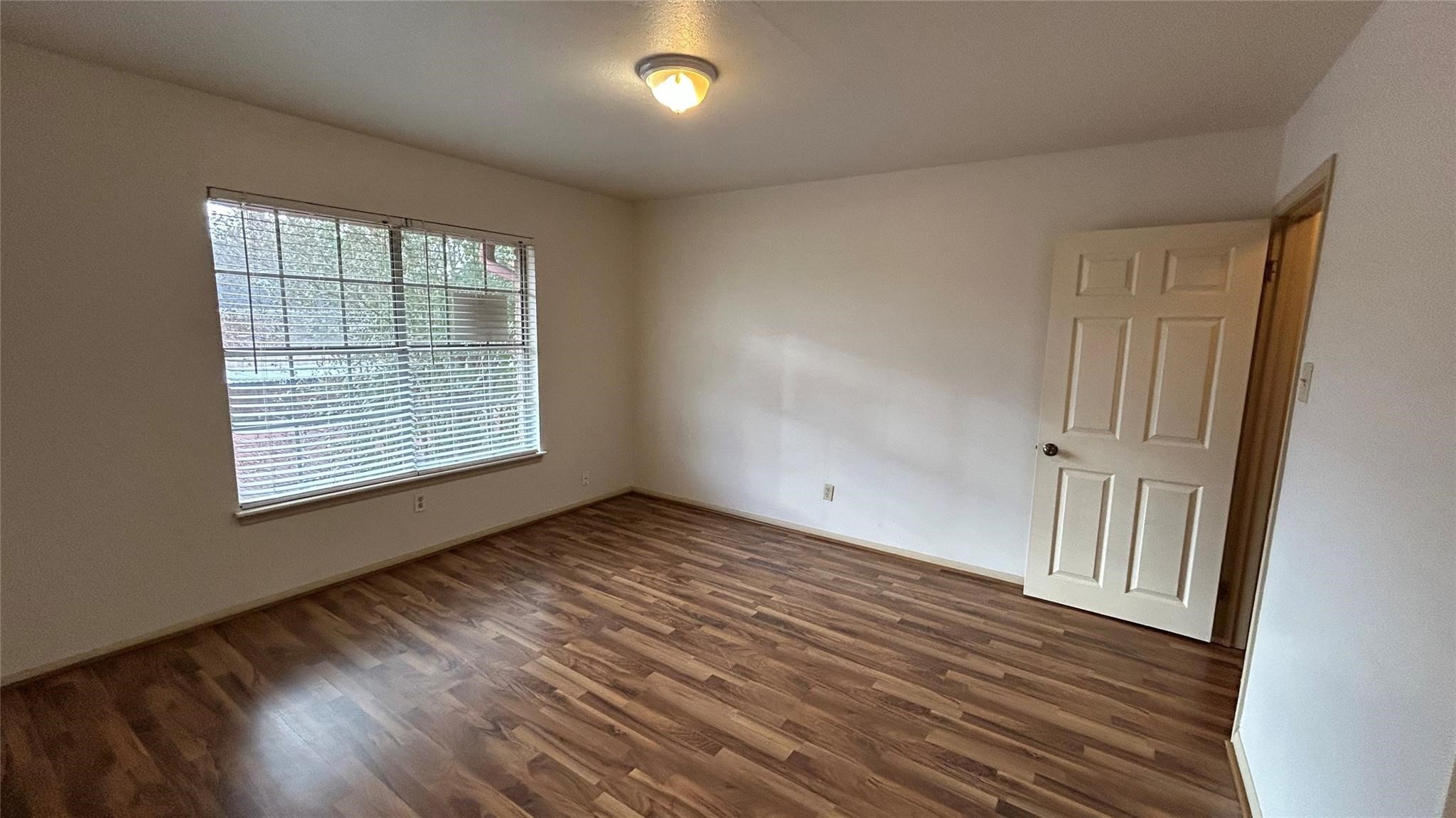 7600 Burgoyne Road, Unit 115 Houston, TX 77063 - Photo 5 of 14 a view of an empty room with wooden floor and a window