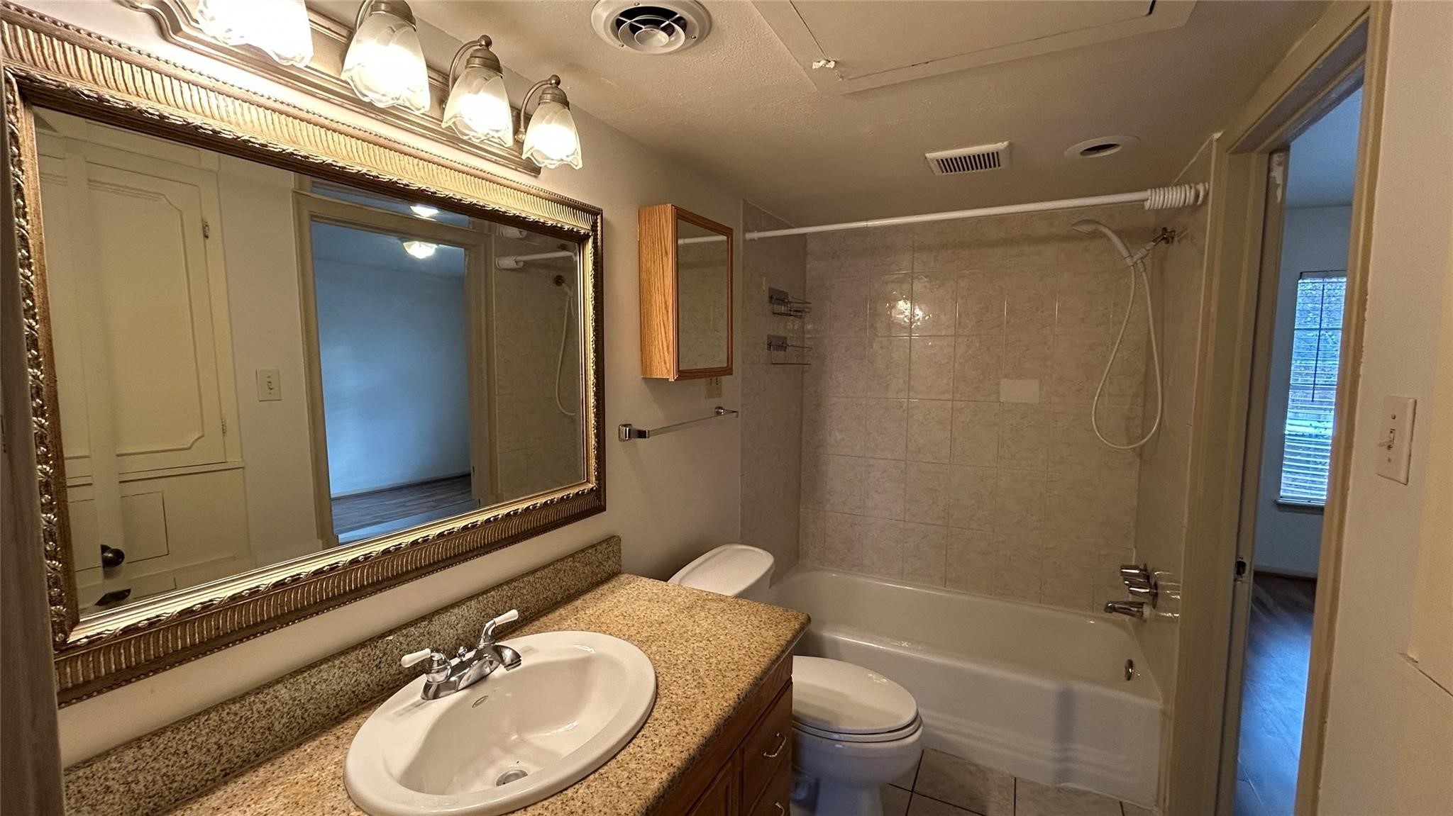7600 Burgoyne Road, Unit 115 Houston, TX 77063 - Photo 7 of 14 a bathroom with a sink a toilet a mirror and shower
