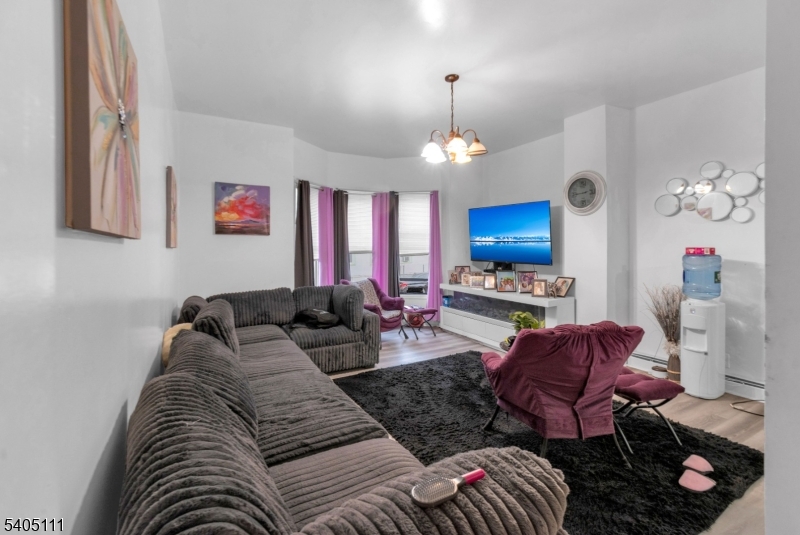 25 Oak Street, Unit 25 Paterson, NJ 07501 - Photo 3 of 25 a living room with furniture a chandelier and a flat screen tv