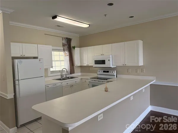 a kitchen with a sink a stove a refrigerator and white cabinets