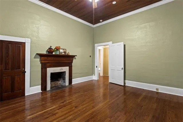 a view of an empty room with wooden floor and a fireplace