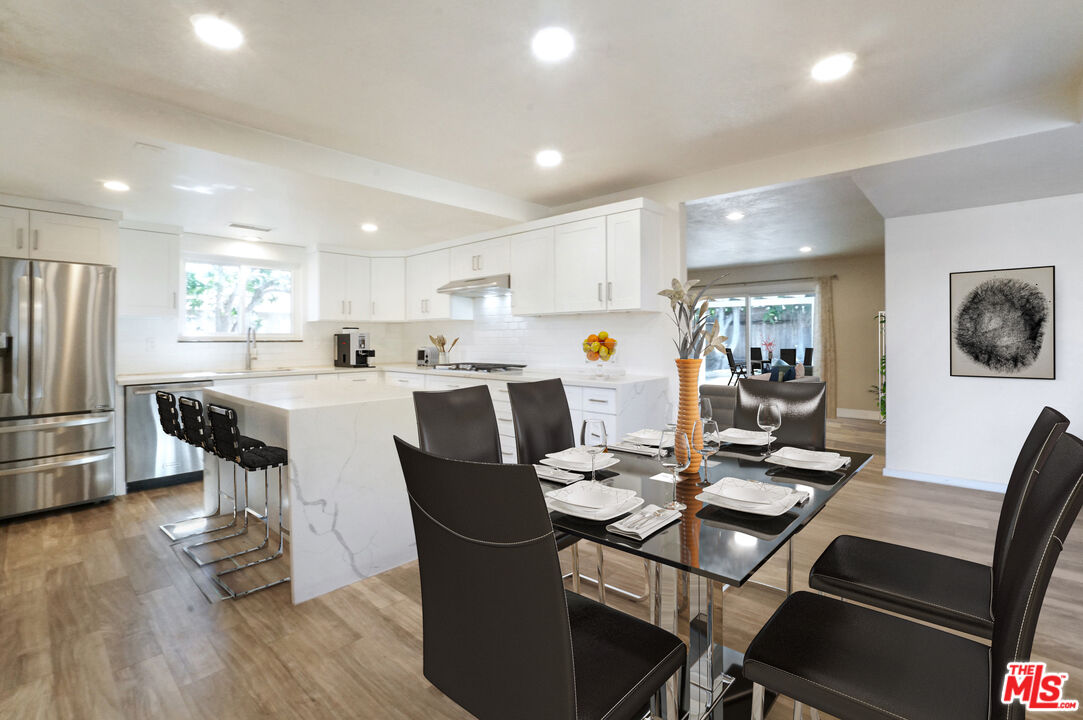 a dining room with stainless steel appliances a dining table and chairs