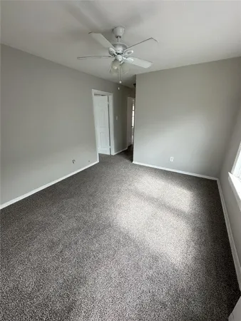 an empty room with a ceiling fan and window