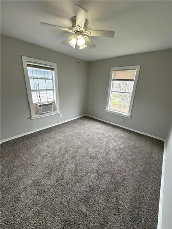 an empty room with windows and fan
