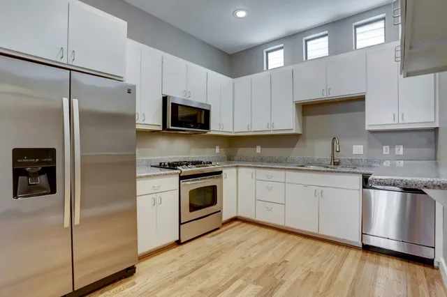 a kitchen with cabinets stainless steel appliances and wooden floor