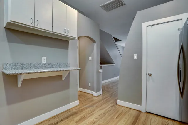a kitchen with granite countertop white cabinets and a stainless steel refrigerator stove