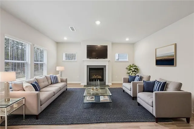 a view of an empty room with wooden floor and kitchen