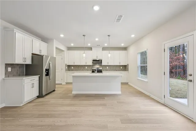 a kitchen with kitchen island granite countertop a sink a counter space stainless steel appliances and cabinets