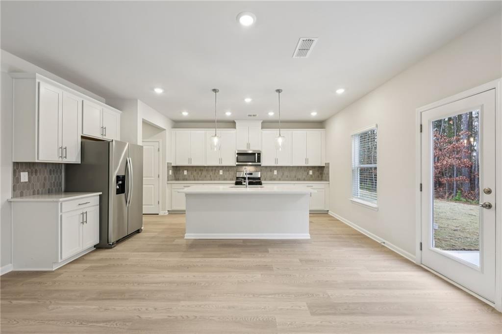 471 Tallulah Lane Grayson, GA 30017 - Photo 10 of 38 a large white kitchen with kitchen island a sink a center island stainless steel appliances and a cabinets