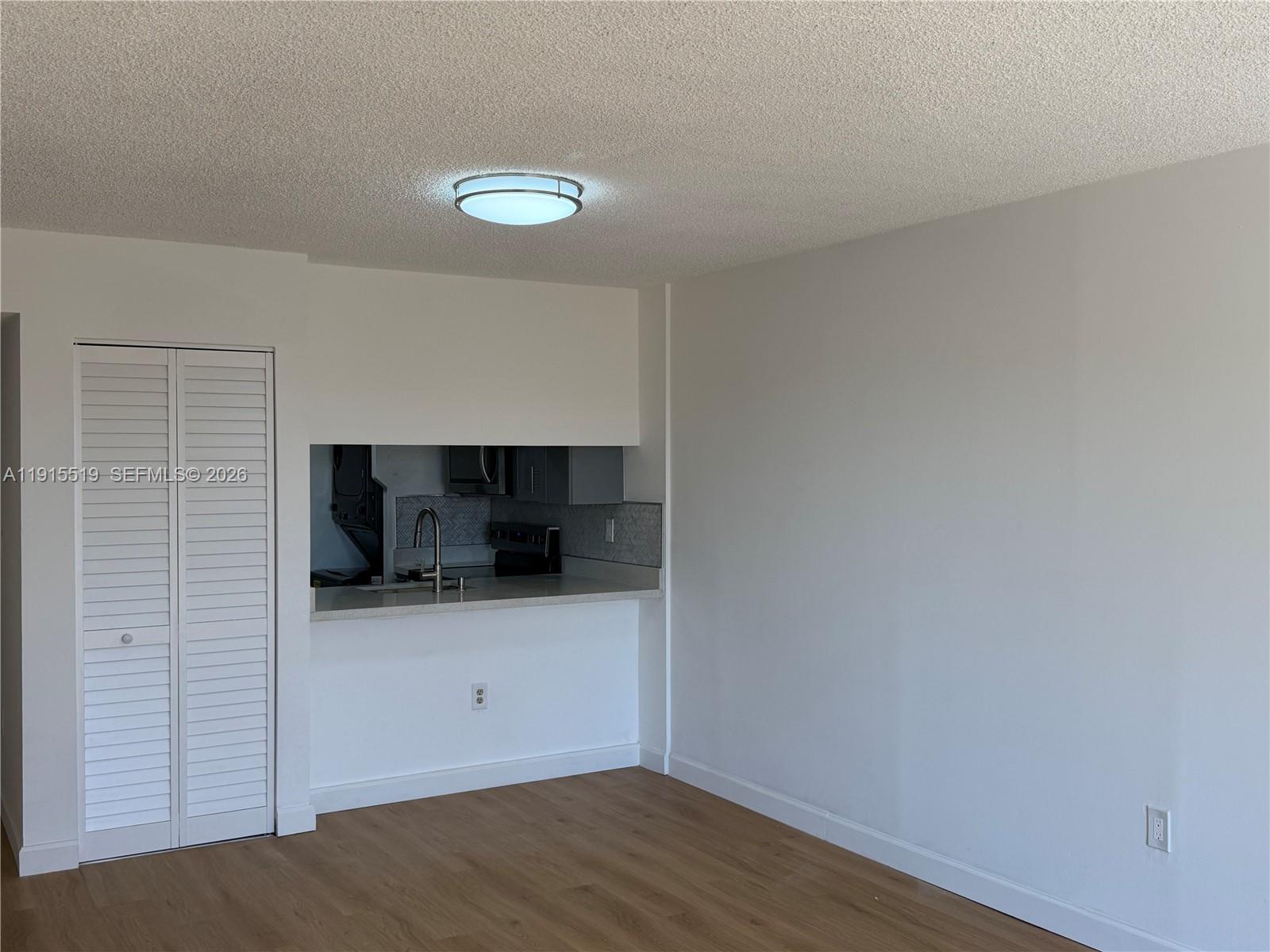 440 East 23rd Street, Unit 1305 Hialeah, FL 33013 - Photo 11 of 15 a view of an empty room and kitchen space with wooden floor