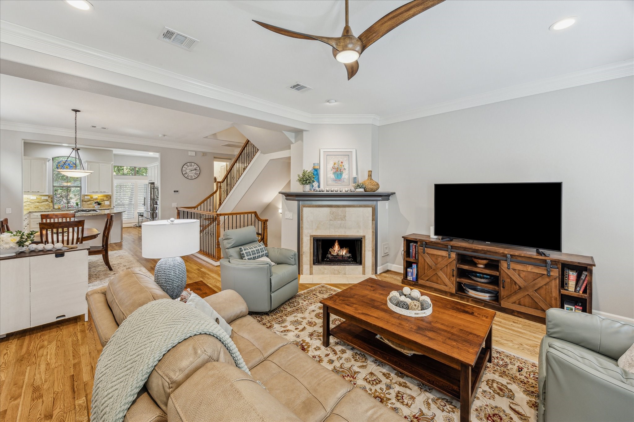 544 Bomar Street Houston, TX 77006 - Photo 18 of 43 FAMILY ROOM... This inviting space features rich hardwood flooring, a cozy gaslog fireplace, and a ceiling fan with an integrated light kit. Recessed lighting and crown molding add a touch of elegance, while the open layout offers clear views into the formal dining area and the gourmet island kitchen—perfect for both everyday living and entertaining.