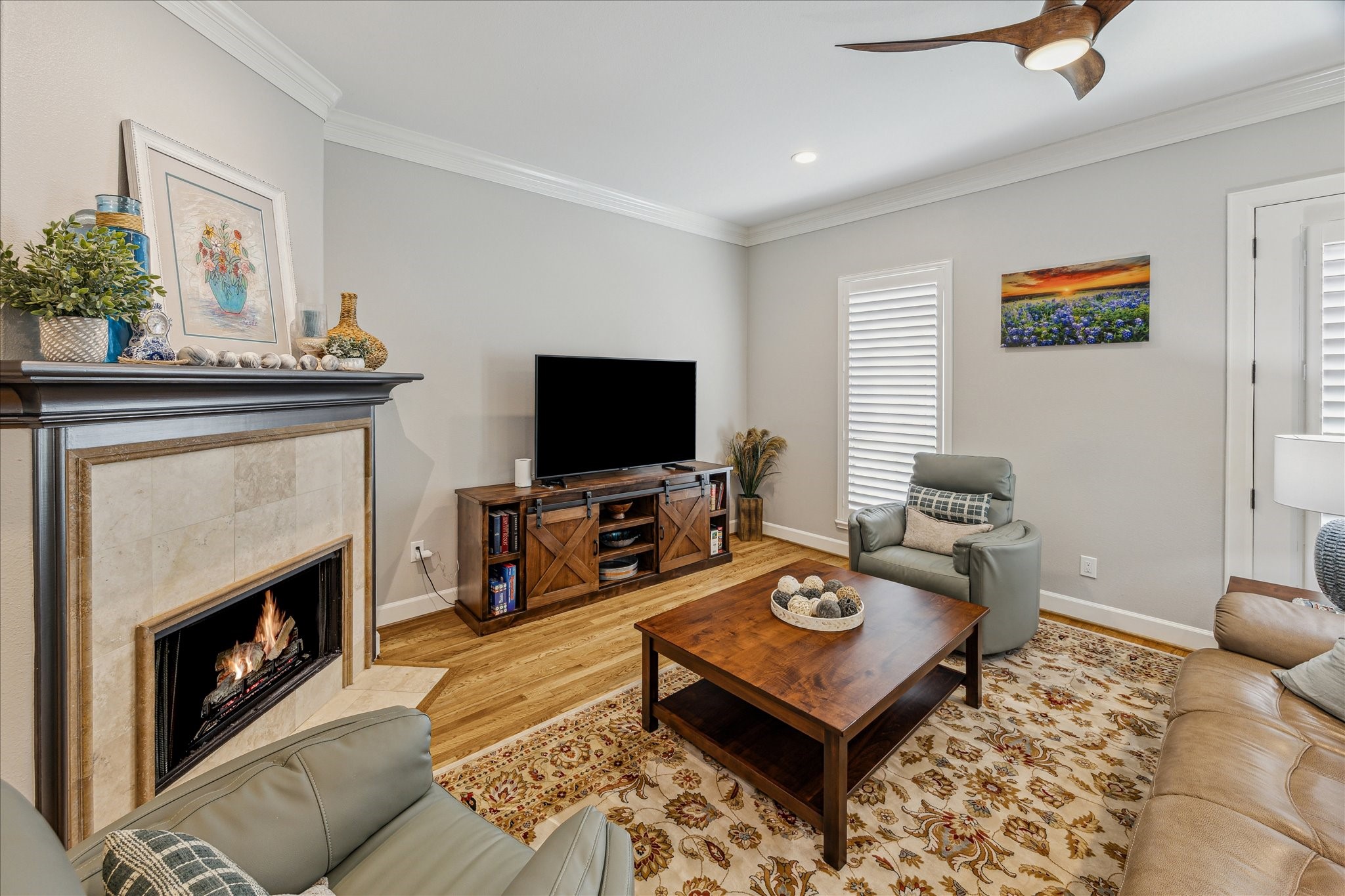 544 Bomar Street Houston, TX 77006 - Photo 20 of 43 FAMILY ROOM... A closer look reveals refined details including art lighting above the traditional fireplace mantel, which is beautifully accented with a ceramic tile surround and matching hearth. Plantation shutters frame the windows, while French doors open to a charming Juliet balcony, blending indoor comfort with outdoor ambiance.