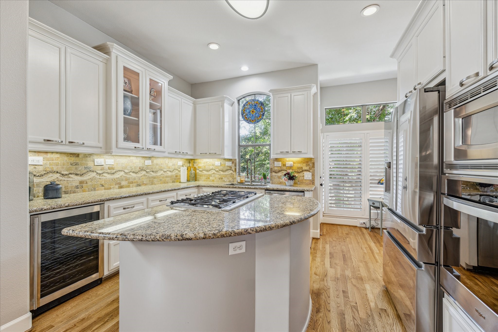 544 Bomar Street Houston, TX 77006 - Photo 22 of 43 GOURMET ISLAND KITCHEN... Designed for both style and function, this chef-inspired kitchen features gleaming granite countertops, a travertine tile backsplash with elegant decorative inlays, and under-cabinet lighting that enhances both ambiance and task visibility. Stainless steel appliances and an expansive island provide ample space for cooking and entertaining, while generous cabinetry ensures abundant storage.
