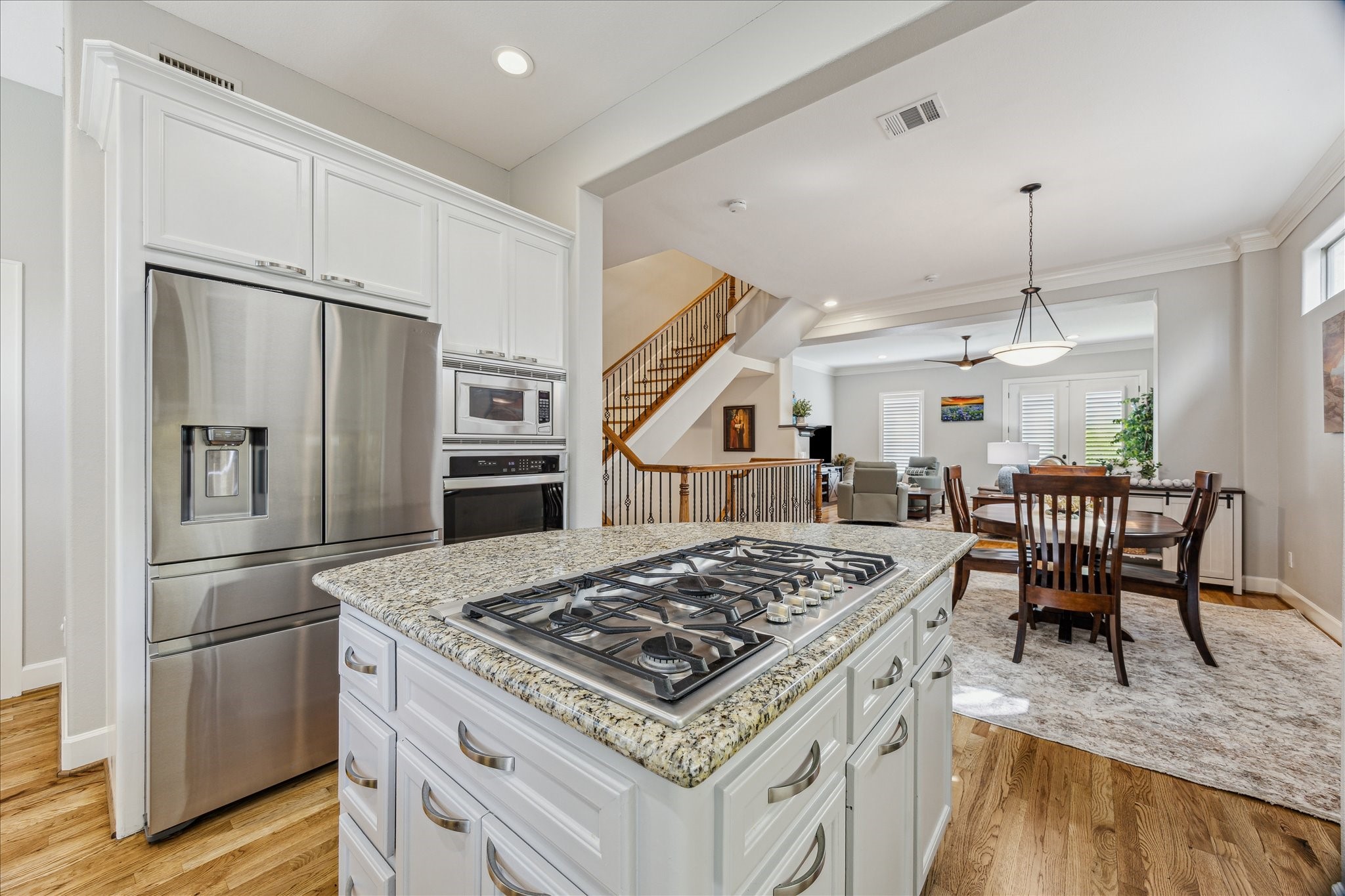 544 Bomar Street Houston, TX 77006 - Photo 23 of 43 A secondary view showcases the seamless integration of the kitchen with the formal dining and family rooms, emphasizing the open-concept design. Featured appliances include a Samsung stainless steel refrigerator/freezer with built-in water and ice dispenser, a Bosch five-burner gas cooktop with downdraft vent hood, and a built-in electric oven and microwave—perfect for the modern home chef.