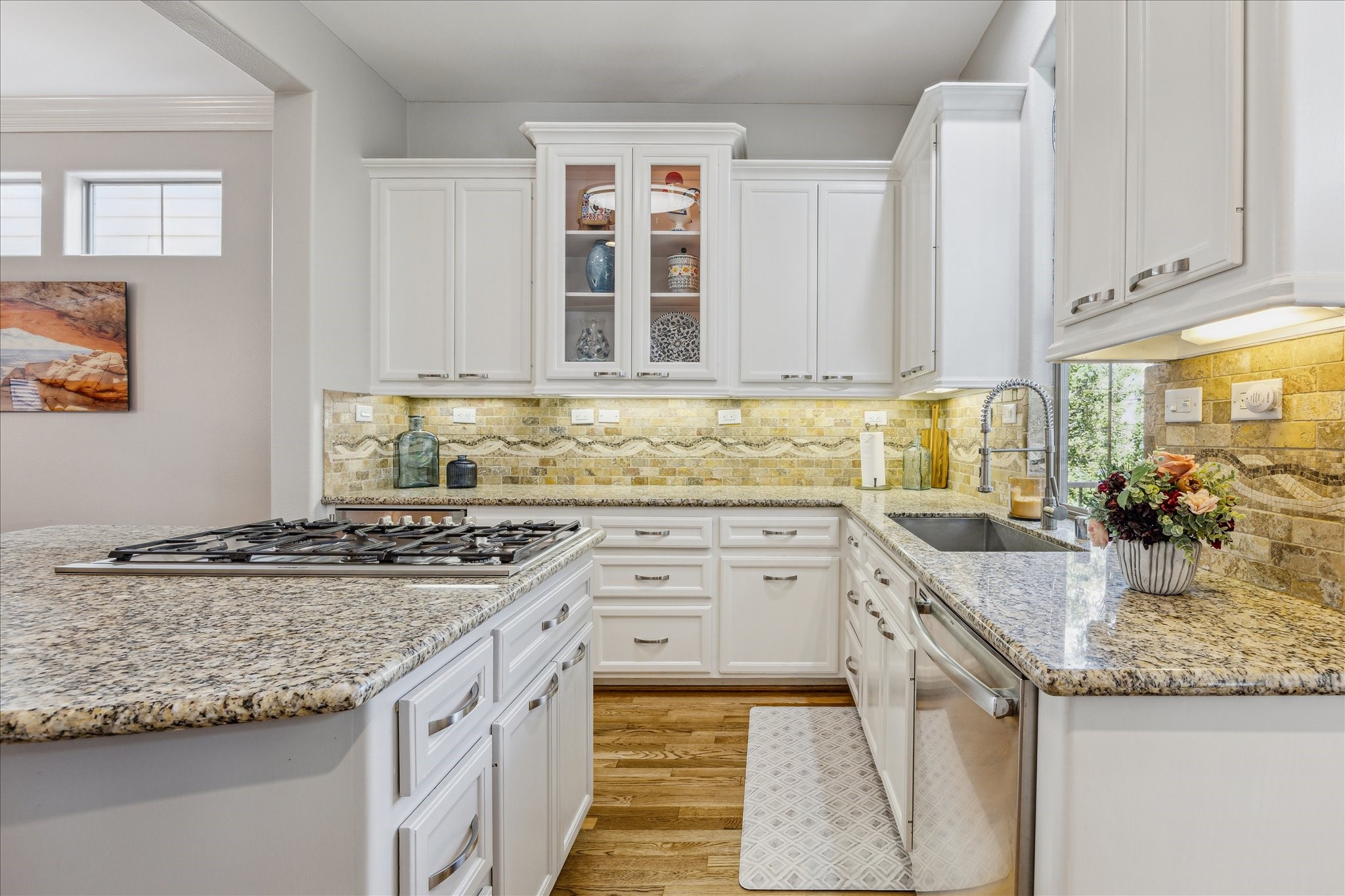 544 Bomar Street Houston, TX 77006 - Photo 24 of 43 Another view highlights the lighted display cabinetry—perfect for showcasing glassware or collectibles—alongside a large drop-in stainless steel sink set beneath an oversized window that fills the space with natural light. These thoughtful details enhance both the functionality and charm of this beautifully designed kitchen.