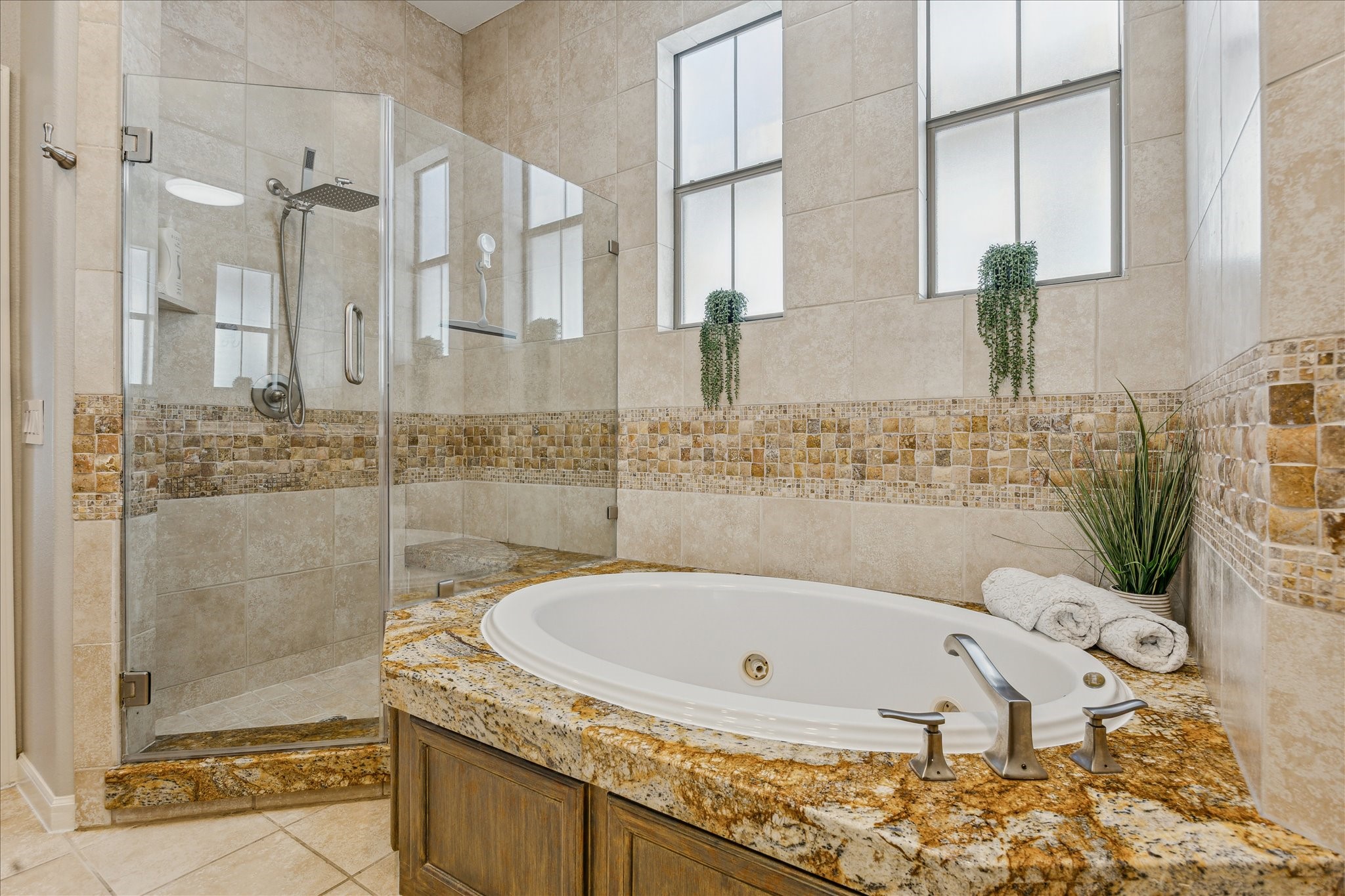 544 Bomar Street Houston, TX 77006 - Photo 33 of 43 This luxurious retreat features a Jacuzzi jetted tub and a frameless walk-in shower with dual shower heads and built-in bench seating. The space is beautifully finished with granite surfaces and ceramic tile walls accented by travertine decorative inlays. Two privacy-glass windows allow natural light while maintaining seclusion, and a separate water closet adds to the comfort and functionality of this serene space.