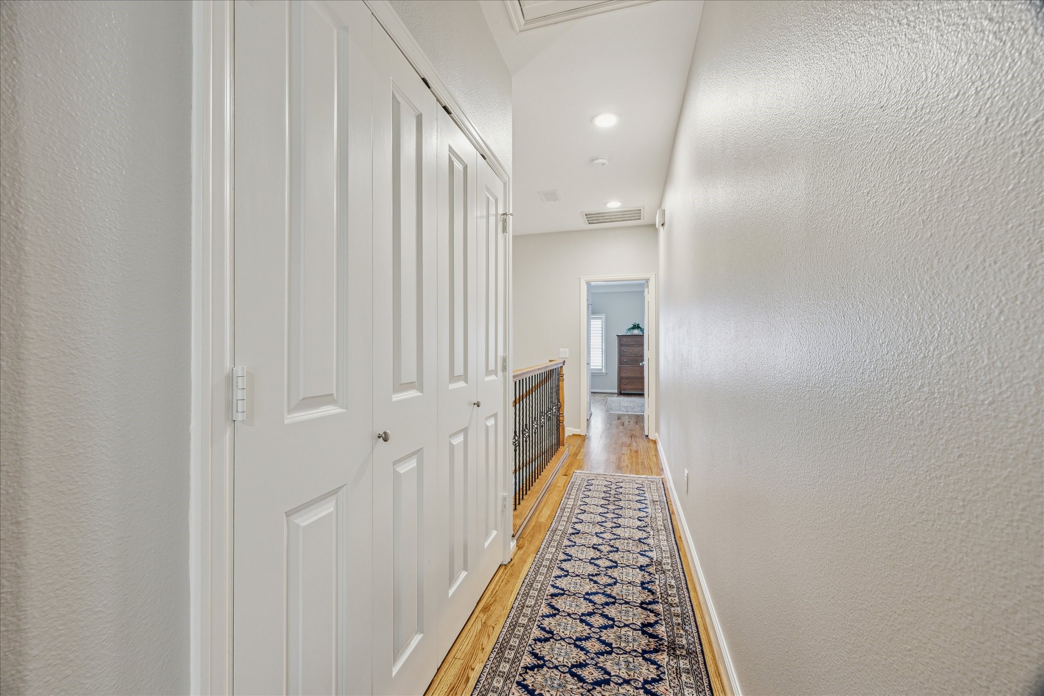 544 Bomar Street Houston, TX 77006 - Photo 36 of 43 HALLWAY... Located on the third floor, this hallway features warm wood flooring and fresh neutral paint, creating a clean and inviting transition between rooms. It offers access to the primary suite, guest suite, and laundry area, with convenient attic access tucked discreetly away.