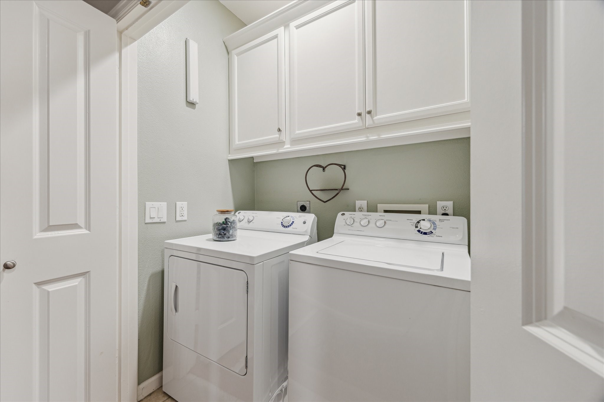 544 Bomar Street Houston, TX 77006 - Photo 37 of 43 LAUNDRY... This well-equipped laundry area includes a full-sized GE washer and gas dryer, both of which remain with the home. The space features durable ceramic tile flooring, an overflow pan for the washer, custom cabinetry for ample storage, and a built-in hanging rack for added convenience. Two bi-fold paneled doors provide easy access while maintaining a clean, streamlined look.