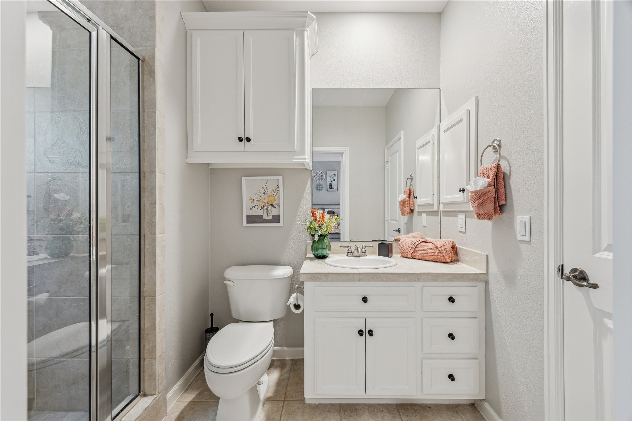 544 Bomar Street Houston, TX 77006 - Photo 39 of 43 ENSUITE BATH... This private bath features ceramic tile flooring and a coordinating ceramic tile countertop. The walk-in shower includes a framed glass enclosure, dual shower heads, and is finished with a ceramic tile surround. A built-in linen cabinet offers convenient storage, while a privacy-glass window brings in natural light without compromising seclusion.