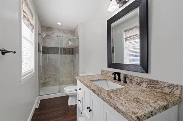 a bathroom with a granite countertop sink toilet and shower