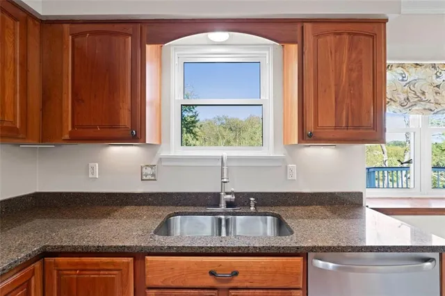 a kitchen with granite countertop stainless steel appliances a sink window and cabinets